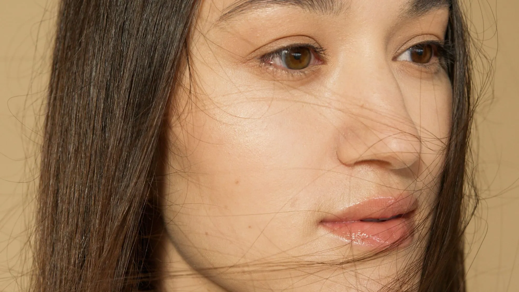 A woman with long dark hair and bare skin, eyes closed, lit softly from the side