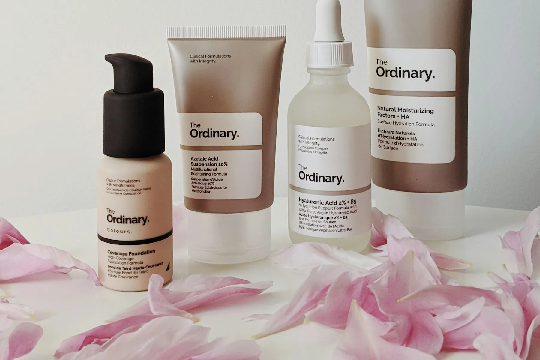A lineup of minimalist skincare bottles and droppers on a pale beige surface