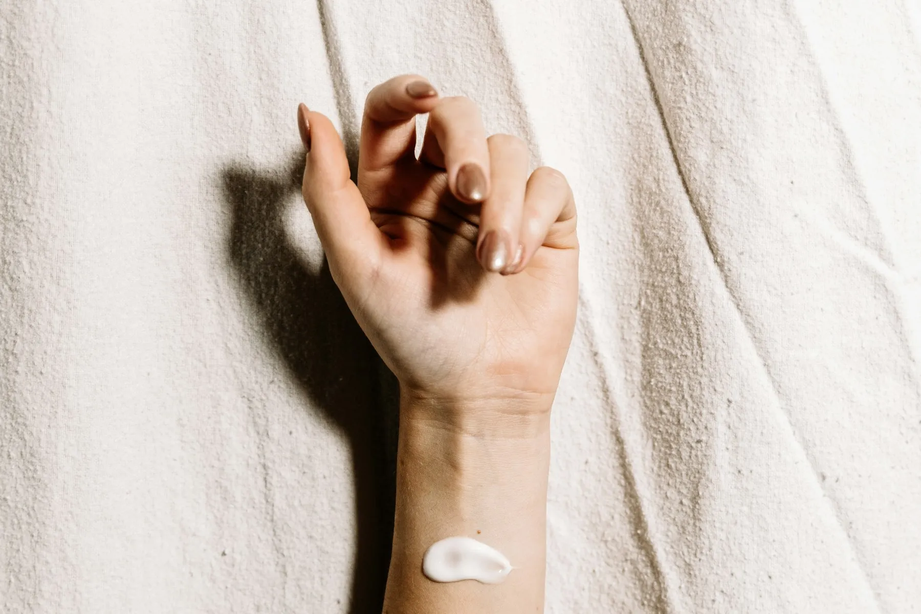 A forearm with three small dabs of white cream applied for testing