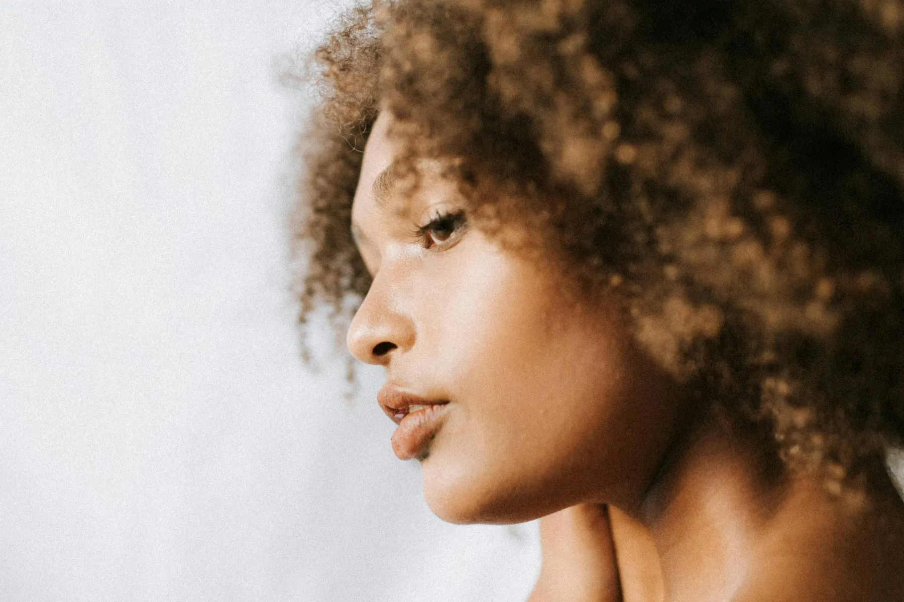 A portrait of a woman with soft natural curls looking to the side