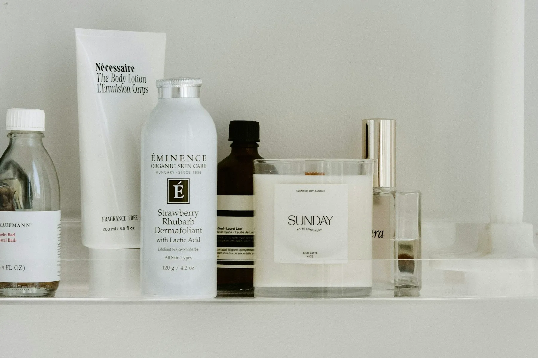 A row of skincare bottles and jars arranged on a white shelf